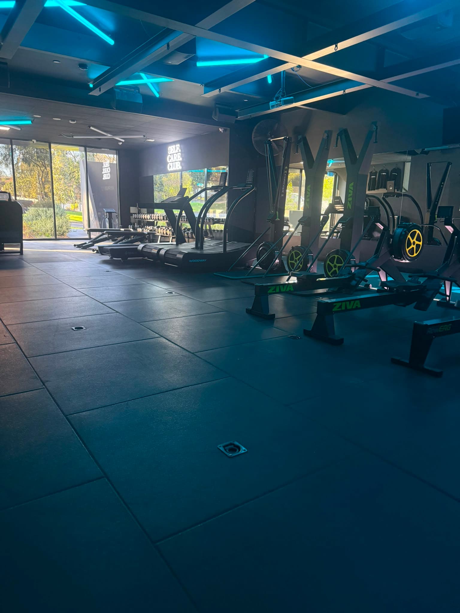 Wide view of The Den training floor with cardio equipment